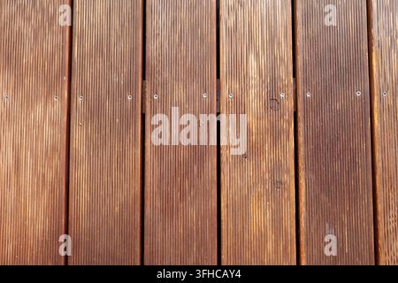Scatto dettagliato dall'alto di listoni di legno marrone paralleli con scanalature antiscivolo testurizzate e viti metalliche, che trasmettono un materiale naturale robusto Foto Stock