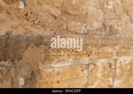 Primo piano di una struttura in pietra antica con dettagli scolpiti e texture di arenaria consumata della Chiesa di Chrysopolitissa a Cipro Foto Stock