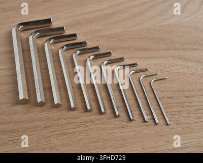 Set di chiavi Torx su sfondo di legno - Una vista dall'alto di una collezione di cacciaviti Torx a forma di L disposti per dimensione su una superficie di legno chiaro per h Foto Stock