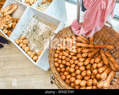 Assortimento di panini freschi e pasticcini esposti in contenitori bianchi e un grande cesto intrecciato. Kampong Cham, Cambogia Foto Stock