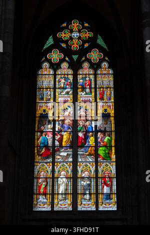 Alto vetrata colorata che mostra una scena religiosa con santi, angeli e colori ricchi all'interno della cattedrale di Colonia. Foto Stock