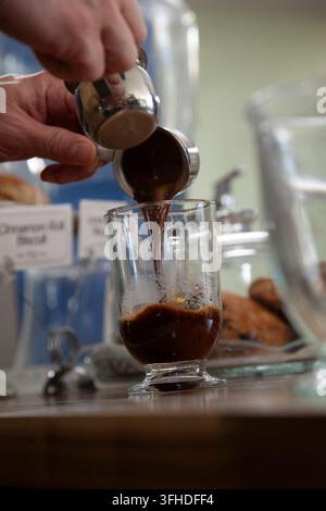 Barista che versa l'espresso in una tazza di vetro Foto Stock
