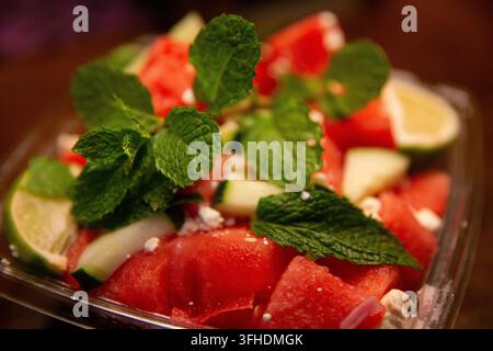 Una fotografia macro dettagliata che cattura un'insalata estiva rinfrescante composta da succosi cubetti di anguria, feta sbriciolata, foglie di menta fresca e Foto Stock