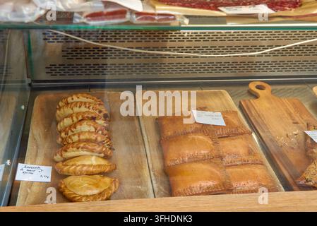 Un primo piano di empanadas salati appena sfornati con manzo e verdure disposti su tavole di legno all'interno di una vetrina di un negozio locale Foto Stock