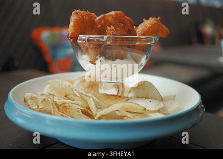 Pezzi di pesce fritti serviti in una ciotola con patatine croccanti su un piatto Foto Stock