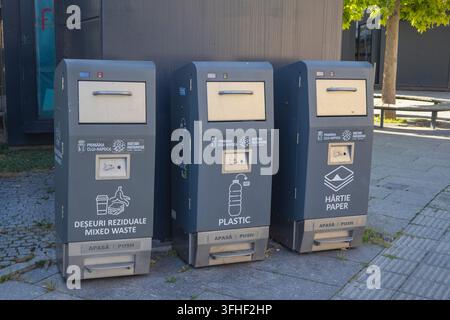 Tre bidoni per lo smaltimento pubblico dei rifiuti per plastica e carta misti su un marciapiede cittadino - Cluj-Napoca, Romania - 16 agosto 2026. Foto Stock