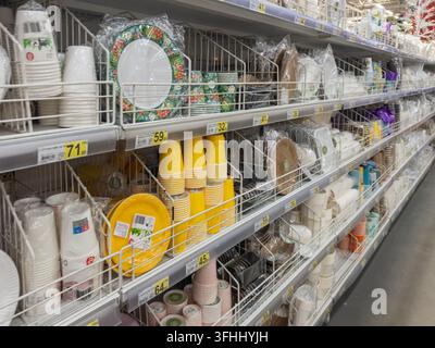Kyiv, Ucraina - 13 marzo 2026: File di varie posate monouso tra cui bicchieri e piatti di carta colorati organizzati per la vendita in un corridoio del negozio per h Foto Stock