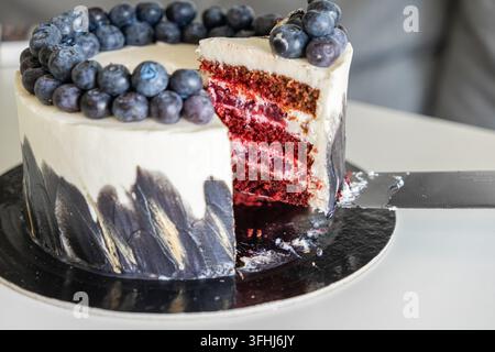 Il dolce decadente presenta strati rossi vivaci con ripieno di panna sormontato da succose bacche, creando così un attraente centrotavola da dessert per una società di alto livello Foto Stock