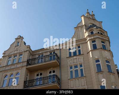 Una facciata residenziale elegante che mostra muratura ornata e design storico, dove i balconi in ferro decorativi si stagliano contro un cielo sereno Foto Stock