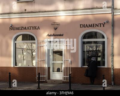 Pozna, Polonia – 28 febbraio 2026: Una persona ispeziona una collezione di collane all'interno della vetrina di un negozio di antiquariato specializzato Foto Stock