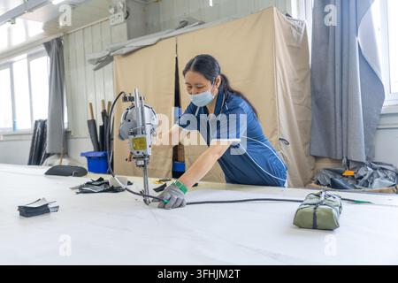 Contea di Luannan, Cina – 30 luglio 2026: Donne che manipolano macchinari da taglio per tagliare tessuti tessili Foto Stock