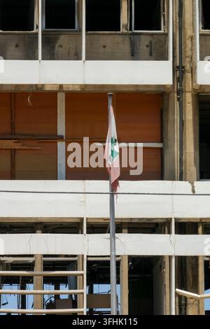 Una bandiera libanese strappata pende da un palo davanti all'edificio della sede di Electricite du Liban danneggiato dall'esplosione del porto di Beirut del 2020, Beirut Go Foto Stock