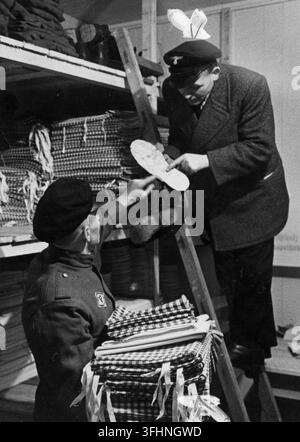 Distribuzione di abiti e calzature in un campo di lavoro nel Reich, 1940, con una guardia tedesca e un lavoratore polacco che indossa una toppa "P". Foto Stock