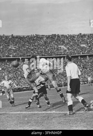Una partita di calcio in un grande stadio, con giocatori svedesi che competono per il pallone in aria, il 20 settembre 1942. Foto Stock