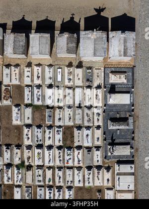 Vista aerea di un cimitero con file di tombe in pietra bianca, croci e lunghe ombre proiettate dai monumenti a Évora, distretto di Évora, Portogallo. Foto Stock