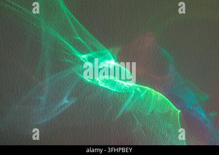 Riflessione di luce verde astratta su una parete ruvida con bagliore neon e motivi colorati fluenti Foto Stock