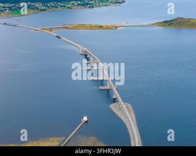 Vista aerea del ponte di Lepsoy che si estende sulle acque blu tra le isole con un piccolo faro e un paesaggio costiero ad Haram, More og Romsdal, Norvegia. Foto Stock