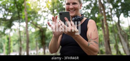 Donna anziana sorridente mentre usa lo smartphone all'aperto Foto Stock