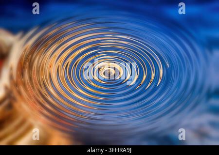 Modello astratto, concentrico, anelli ondulati, centro, tema vortici, profondità, movimento, contrasto, oro, ambra, blu, caldo, freddo, spirale, onde sull'acqua surfa Foto Stock