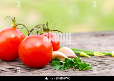Tre pomodori rossi sono su un tavolo di legno Foto Stock