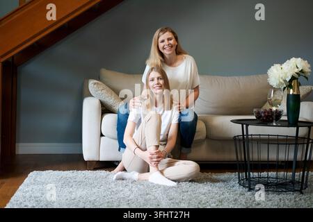 Ritratto di una madre anziana e di una figlia matura che si abbracciano a casa. Mamma anziana felice e figlia adulta che si abbracciano amorevolmente sul divano del soggiorno. Ca Foto Stock