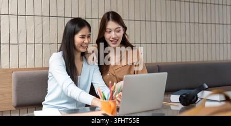 Esplorare idee e apprendimento collaborativo. Due studenti che lavorano insieme su un notebook mentre si divertono. Foto Stock