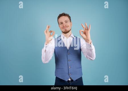 Immagine di un uomo di successo in abito formale che sorride alla telecamera, isolato su blu Foto Stock