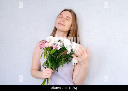 Una donna tiene un mazzo di fiori e sorride Foto Stock