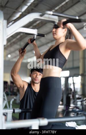 Benessere e fitness Coaching. Un personal trainer che guida una donna su una macchina pull-up. Foto Stock