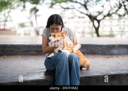 Momento Corgi affettuoso. Donna che coccola il suo cane in un ambiente tranquillo all'aperto. Foto Stock