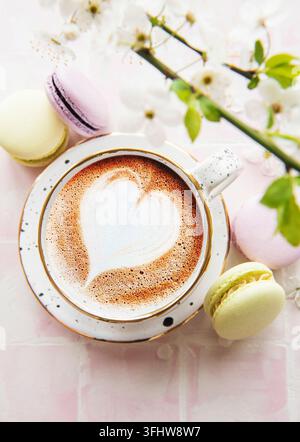 Caffè con un motivo a forma di cuore e dolci dessert di macarons Foto Stock