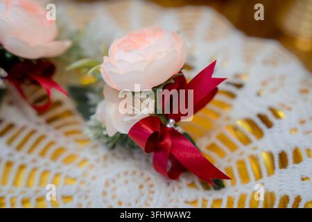 Bellissima boutonniera di rose rosa decorata con un nastro rosso per un matrimonio Foto Stock