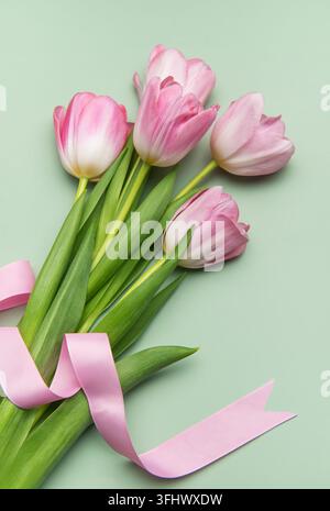 Tulipani rosa con nastro su sfondo verde pastello per le vacanze primaverili Foto Stock
