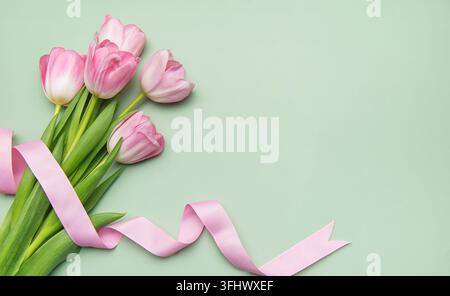Tulipani rosa con nastro su sfondo verde pastello per le vacanze primaverili Foto Stock