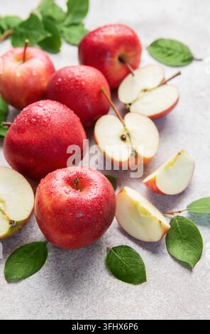 Mele rosse fresche con foglie verdi su sfondo grigio Foto Stock