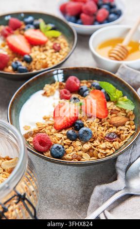Ciotole di granola con frutti di bosco, yogurt, noci e miele per la colazione Foto Stock