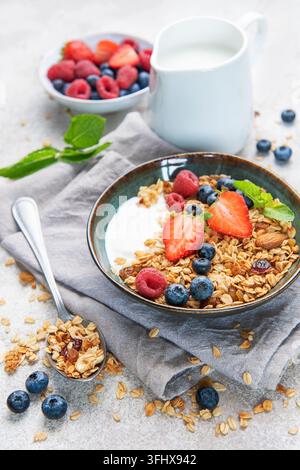 Ciotole di granola con frutti di bosco, yogurt, noci e miele per la colazione Foto Stock