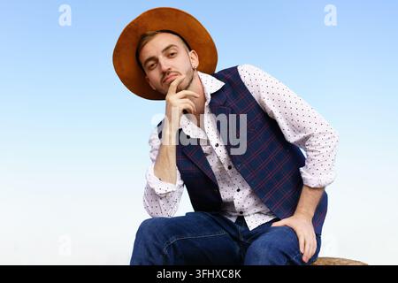 Ritratto di un giovane uomo adulto con cappello, camicia bianca e gilet sullo sfondo della natura Foto Stock