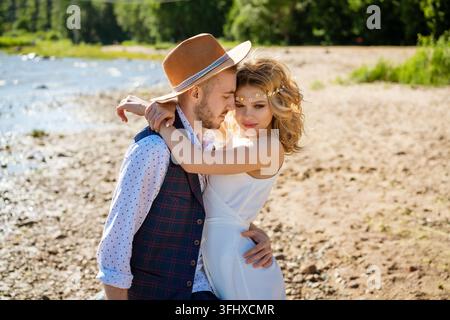 Una coppia innamorata, vestita con abiti semplici, si abbraccia sulla riva del mare. Concetto di felicità. Foto Stock