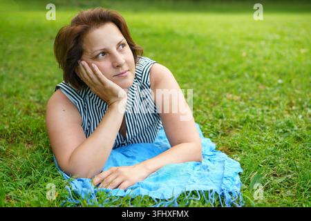 Donna carina e felice sdraiata sull'erba verde a riposo Foto Stock
