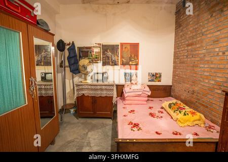 Camera da letto vintage con biancheria da letto rosa, TV in bianco e nero e pareti in mattoni rossi Foto Stock