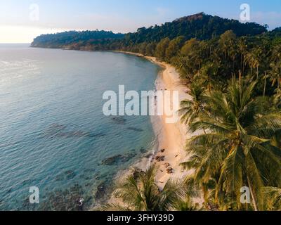 Scopri le tranquille rive della spiaggia di Takhian a Koh Kood, Thailandia. La sabbia dorata e le lussureggianti palme creano una fuga perfetta per rilassarsi e fare un po' di musica Foto Stock