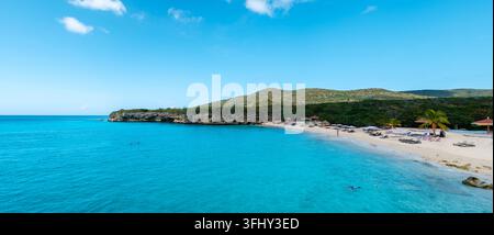 I visitatori possono godersi una giornata di sole alla spiaggia di Grote Knip a Curacao, circondata da splendide acque turchesi e colline lussureggianti. Foto Stock
