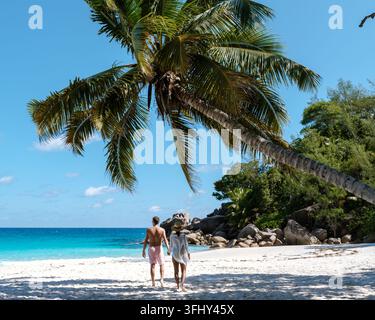 Passeggia in coppia lungo la spiaggia incontaminata di Anse Georgette a Praslin Seychelles, godendoti il caldo sole, la sabbia soffice e le acque turchesi. Una ge perfetta Foto Stock