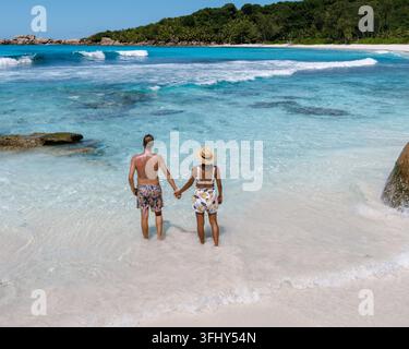 Le limpide acque turchesi si infrangono contro le soffici sabbie bianche della spiaggia di Anse Cocos, mentre un paio di passegge mano nella mano, godendosi la loro romantica vacanza in tro Foto Stock