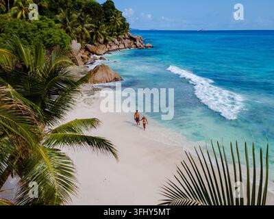 Una coppia che si gode una romantica passeggiata lungo la morbida spiaggia sabbiosa di Anse Patates. Acque turchesi e vegetazione lussureggiante creano un perfetto paradiso tropicale, Foto Stock