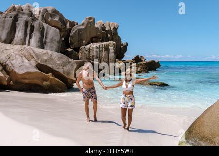 Coppia che si gode una giornata di sole alla spiaggia di Anse Cocos a la Digue, Seychelles. Foto Stock