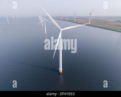 Una vista mozzafiato di un parco eolico offshore nei Paesi Bassi. Le turbine giganti si ergono alte, generando elettricità pulita e mostrando quelle del paese Foto Stock