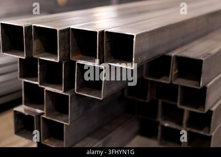 Profilati scatolati in metallo impilati in file presso lo stabilimento di stoccaggio industriale con sezione trasversale Foto Stock