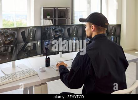Addetto alla sicurezza moderno che osserva i feed CCTV nella sala di controllo della sorveglianza Foto Stock